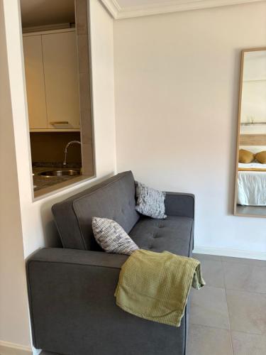 a gray couch in a living room with a mirror at Estudio central in Oviedo
