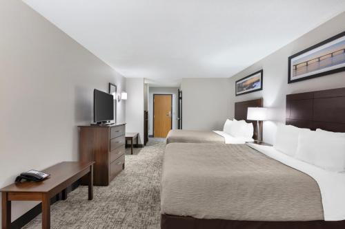 a hotel room with two beds and a flat screen tv at Quality Inn Columbia Mall in Grand Forks
