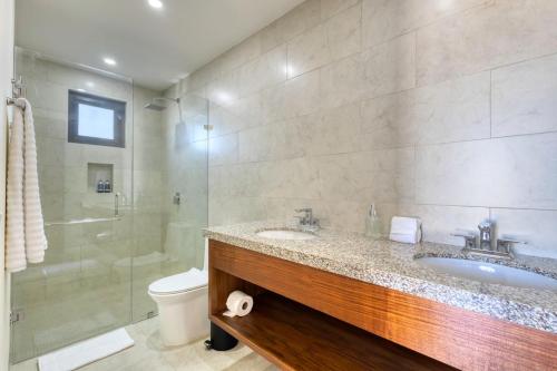 a bathroom with two sinks and a shower and a toilet at New 3 BD Condo with Pool and Gym in Cabo San Lucas