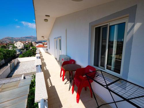 a balcony with red chairs and a table on a building at Daydream Villas in Shkodër