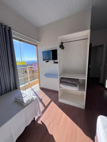 Cette chambre comprend un lit, une télévision et une fenêtre. dans l'établissement Pousada Ponto Chic, à São Miguel Arcanjo