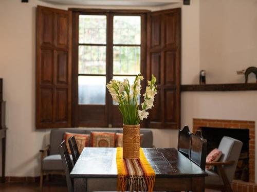 a dining room table with a vase of flowers on it at Apartamentos Antigua in Antigua Guatemala