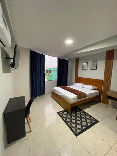 a bedroom with a bed and a desk and a television at Suites Avenida in Machala