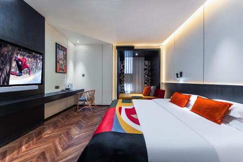 a hotel room with a large bed and a tv at HeSu Hidden Art Hotel & Suites - Near Bell Tower & Ideal Location-Spacious rooms featuring King or Double Queen beds -Exclusive Two&Three-Bedroom Suites with Expansive Living Rooms for Group Gathering-Kitty Cuddles & Coffee Gift -Seamless Journey Planning in Xi'an
