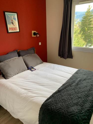 una camera da letto con un grande letto bianco con una finestra di Appartement à Saint Lary Soulan, 4-5 pers, à 150m des télécabines et du village avec piscine a Saint-Lary-Soulan