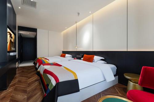 a bedroom with two beds and a red chair at HeSu Hidden Art Hotel & Suites - Near Bell Tower & Ideal Location-Spacious rooms featuring King or Double Queen beds -Exclusive Two&Three-Bedroom Suites with Expansive Living Rooms for Group Gathering-Kitty Cuddles & Coffee Gift -Seamless Journey Planning in Xi'an