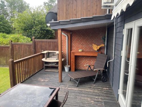 a patio with a table and a chair on a deck at Dreibogen Ferienwohnung Lolle in Glücksburg