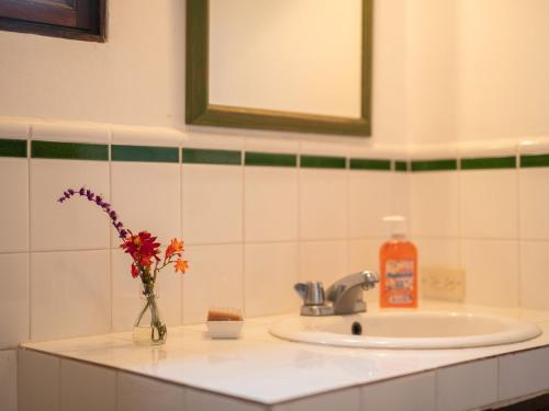 a bathroom sink with a vase of flowers and a bottle of soap at Apartamentos Antigua in Antigua Guatemala