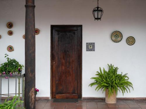 a wooden door on a white wall with a plant at Apartamentos Antigua in Antigua Guatemala