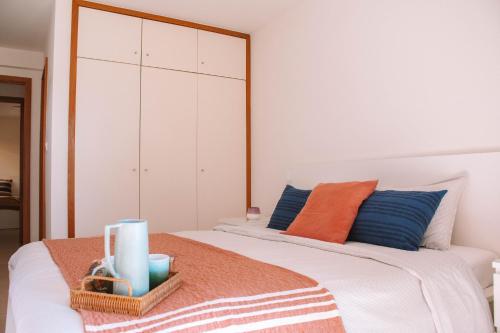 a bedroom with a white bed with blue and orange pillows at Just Like Home - Casa Lima in Caminha