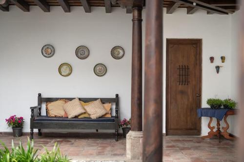 a porch with a bench with pillows and plates on the wall at Apartamentos Antigua in Antigua Guatemala