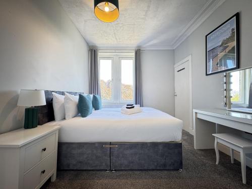 a white bedroom with a large bed and a desk at 56 Degrees North in Kirkcaldy