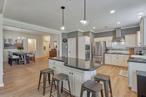 a large kitchen with white cabinets and bar stools at Woodlands Grand 3BR Cozy House in The Woodlands