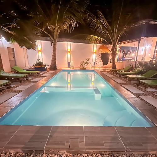 a swimming pool at night with palm trees at Ondo House in Nungwi