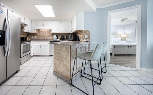 a kitchen with white cabinets and a counter with stools at Phoenix IV 4053 condo in Orange Beach