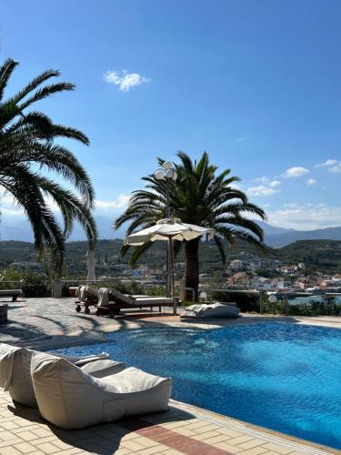 a swimming pool with palm trees and an umbrella at Apartment Sunkiss in Almirida