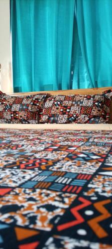 a bed with a blue curtain and a rug at Le Hublot Bénin in Cotonou