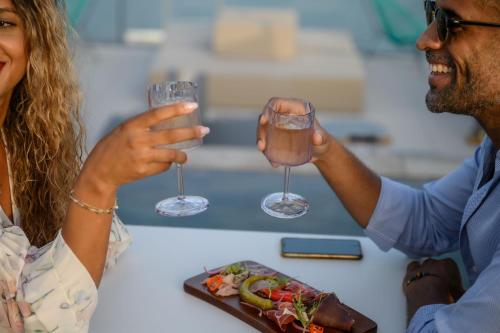 勒马兰Sable Bleu Boutique Hotel的两个人在一盘食物前举着酒杯