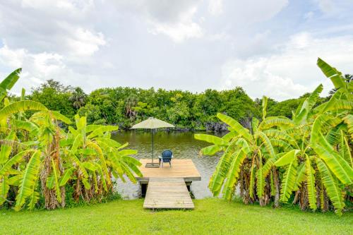 a wooden dock with a chair and an umbrella on the water at Port Charlotte Home with Sunroom, Grill and Fire Pit! in Port Charlotte