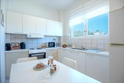 eine Küche mit weißen Schränken und einem weißen Tisch mit Stühlen in der Unterkunft 4Seasonsapts in Agios Nikolaos