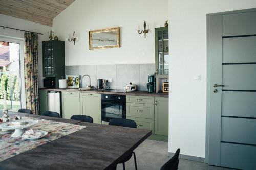 a kitchen with a wooden table and a kitchen with green cabinets at Słoneczna Bryza - domek, pokoje i apartamenty in Gąski