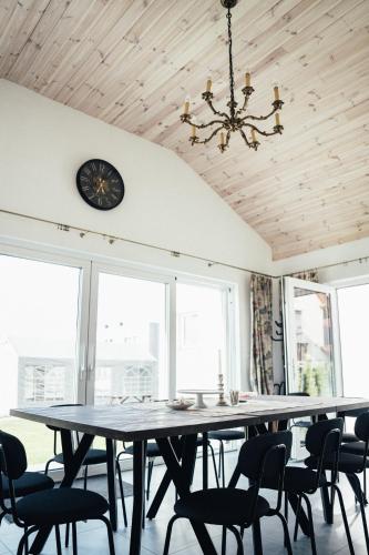 a dining room with a table and chairs and a clock at Słoneczna Bryza - domek, pokoje i apartamenty in Gąski