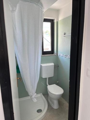 a bathroom with a white toilet and a window at Odisej House Tolmin in Tolmin