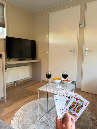 a person holding up a card game with two glasses of wine at Chalet Boerennest bij strand en duinen - Midicamping Van der Burgh - Rockanje in Rockanje