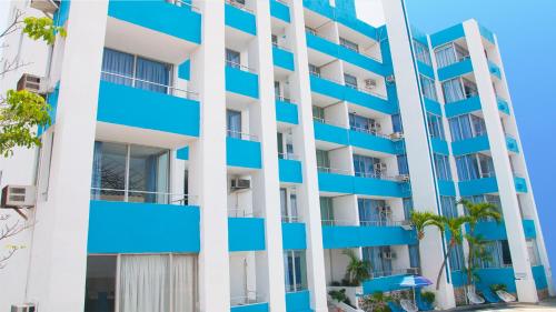 an apartment building with blue balconies and palm trees at Dorados Acapulco in Acapulco