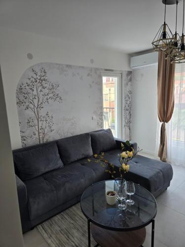 a living room with a blue couch and a glass table at I&I Apartments Lux in Kragujevac
