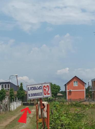a street sign with a red arrow next to a house at Natali & Giga in Ureki