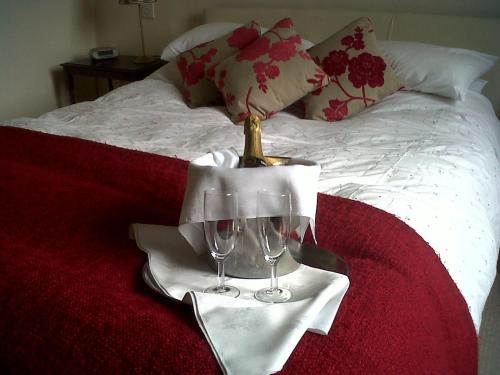 a table with two wine glasses on a bed at The Hand Hotel Llangollen by Compass Hospitality in Llangollen