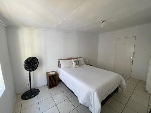 a white bedroom with a bed and a fan at Evergreen Avocado Orchard in Alexandria
