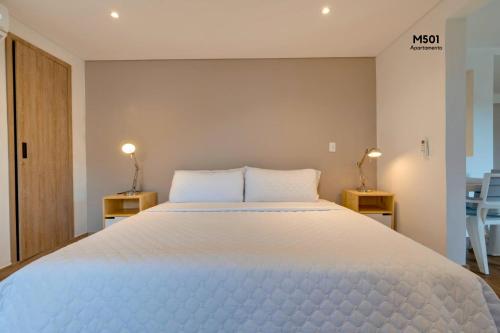 a bedroom with a large white bed with two lamps at Magusan Holiday Rentals in Cali