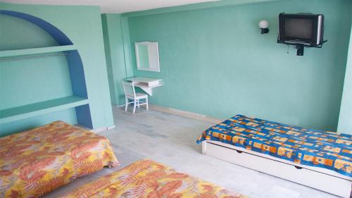 a bedroom with two beds and a tv on the wall at Dorados Acapulco in Acapulco