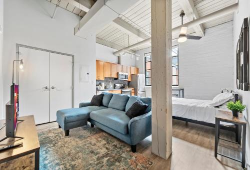 a living room with a blue couch and a bed at Studio at Superior l Downtown l Parking l Café in Cleveland