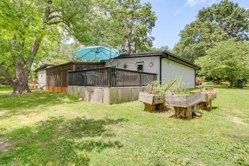 a tiny house with a deck and an umbrella at Walk to Lake Fayetteville Family Retreat with Deck in Springdale