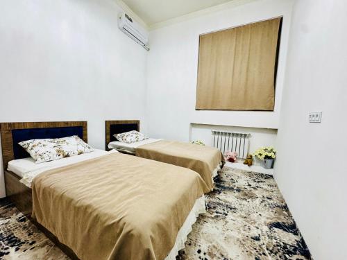 two beds in a room with white walls at Komolon in Tashkent