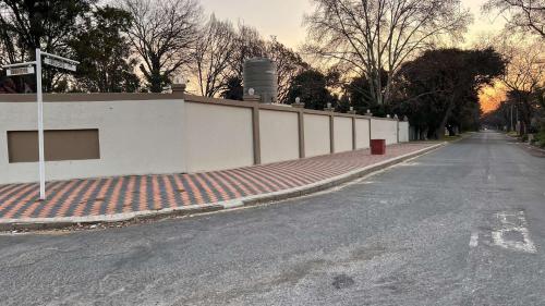 an empty street with a white wall and a street sign at Los Angeles Lakefield guesthouse in Benoni