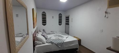a bedroom with a bed with a mirror and shoes on the wall at Hospedagem da Néli in Aparecida