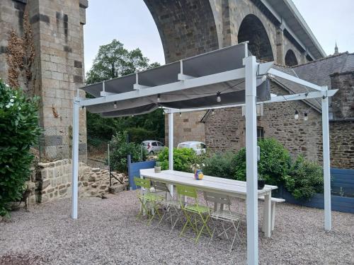 a picnic table under an umbrella in front of a building at Studio de la Maison Bleue in Lanvallay