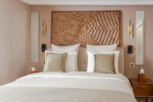 une chambre avec un grand lit avec des draps et des oreillers blancs dans l'établissement Luxury Living in Paris 1er - Palais Royal, Victoires-louvre, à Paris