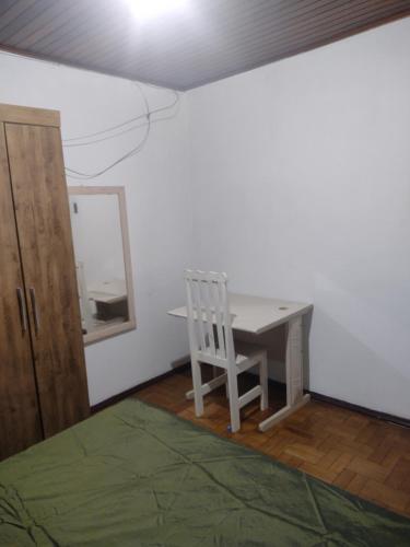 a room with a table and a chair and a mirror at Casa de hospedagem in Blumenau