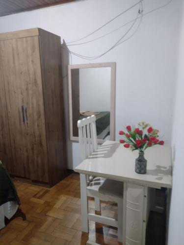 a white table and chair with a vase of flowers on it at Casa de hospedagem in Blumenau