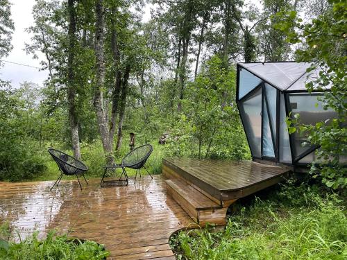 a glass house with two chairs on a wooden deck at Hekso treehouse in Kiriku