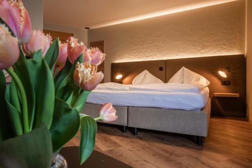 a hotel room with a bed and a vase of flowers at Hotel Châlet Du Lac in Iseltwald