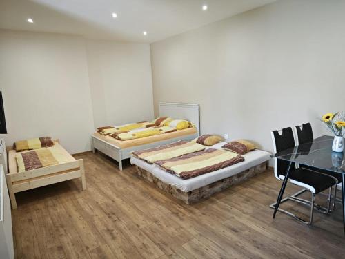 two beds in a room with a table and chairs at Mendi in Štúrovo