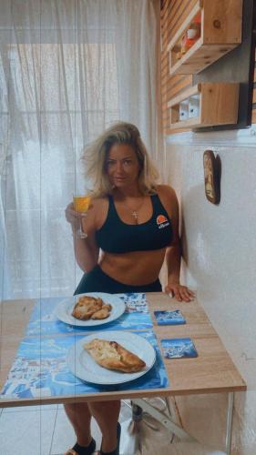 a woman sitting at a table with a plate of pizza at Queen Suites Family Friendly 60m2 in Thessaloniki