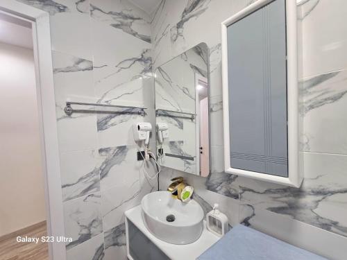 a white bathroom with a sink and a mirror at Apartment, premium class, near the sea 1718 batumi in Batumi