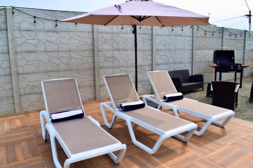 three white chairs and an umbrella in a room at Tiny House con Piscina Privada, Jacuzzi, Parrilla y Starlink in Punta Negra